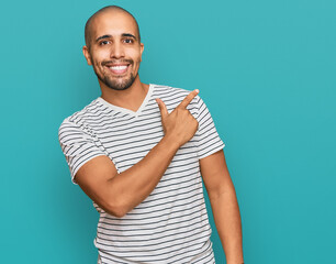 Wall Mural - Hispanic adult man wearing casual clothes cheerful with a smile of face pointing with hand and finger up to the side with happy and natural expression on face