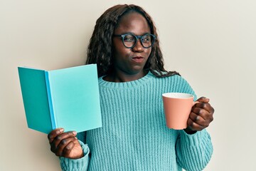 Poster - African young woman reading a book and drinking a cup of coffee skeptic and nervous, frowning upset because of problem. negative person.