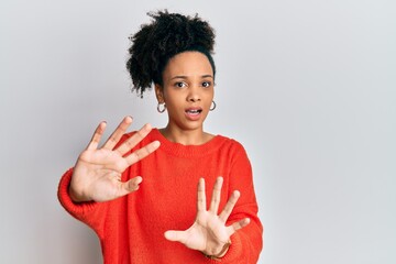 Poster - Young african american girl wearing casual clothes afraid and terrified with fear expression stop gesture with hands, shouting in shock. panic concept.