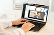 © golubovy - Web chat. Digital conference. Online meeting. Pandemic WFH. Woman working from home with Asian male partner in headphones on laptop screen hands typing on keyboard at modern workplace.