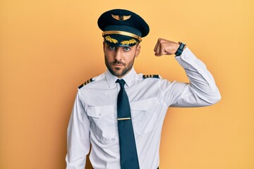 Sticker - Handsome hispanic man wearing airplane pilot uniform strong person showing arm muscle, confident and proud of power