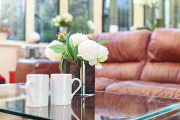 Two cups of tea or coffee together on a coffee table in a light home interior room