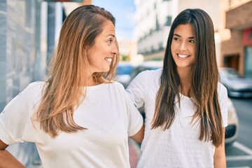 Wall Mural - Beautiful hispanic mother and daughter smiling happy standing at the city.