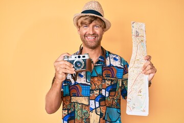 Sticker - Young blond man holding vintage camera and city map smiling with a happy and cool smile on face. showing teeth.