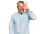 © Krakenimages.com - Middle age grey-haired man wearing casual clothes doing ok gesture with hand smiling, eye looking through fingers with happy face.
