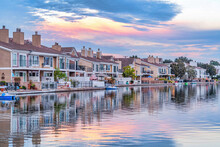Homes In Huntington Beach With View Of Water Reflecting Cloudy Sky At Sunset