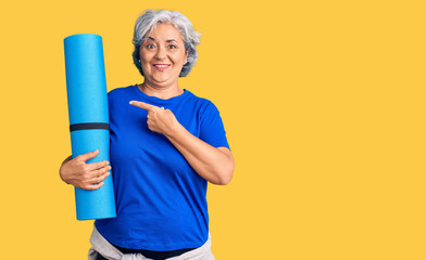 Poster - Senior woman with gray hair holding yoga mat smiling happy pointing with hand and finger