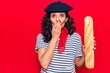 © Krakenimages.com - Middle age beautiful woman wearing french beret holding baguette covering mouth with hand, shocked and afraid for mistake. surprised expression
