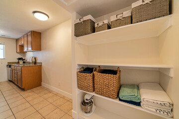 Wall Mural - Kitchen counter with hanging cabinets adjacent to wall shelves inside a house