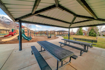 Wall Mural - Pavilion with picnic tables and view of kids playground mountain and cloudy sky