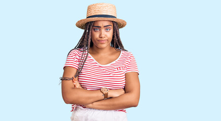 Sticker - Young african american woman with braids wearing summer hat skeptic and nervous, disapproving expression on face with crossed arms. negative person.