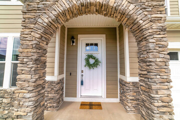 Wall Mural - Arched entrance made of stone bricks leading to white front door with wreath