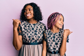 Sticker - Beautiful african american mother and daughter wearing sexy party dress smiling with happy face looking and pointing to the side with thumb up.