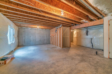 Room under construction with plastic cover on wall and exposed wood beams