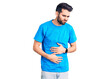© Krakenimages.com - Young handsome man with beard wearing casual t-shirt with hand on stomach because indigestion, painful illness feeling unwell. ache concept.
