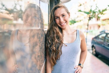 Sticker - Young blonde woman smiling happy leaning on the wall at street of city