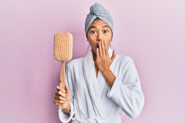 Wall Mural - Young chinese woman wearing shower towel cap and bathrobe holding sponge covering mouth with hand, shocked and afraid for mistake. surprised expression