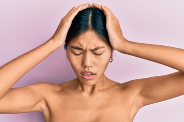 Sticker - Young chinese woman standing topless showing skin suffering from headache desperate and stressed because pain and migraine. hands on head.