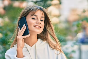 Caucasian sporty teenager girl smiling happy talking on the smartphone at the city.