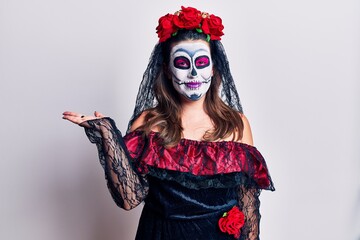 Sticker - Young woman wearing day of the dead costume over white smiling cheerful presenting and pointing with palm of hand looking at the camera.