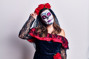 Canvas Print - Young woman wearing day of the dead costume over white smiling confident touching hair with hand up gesture, posing attractive and fashionable