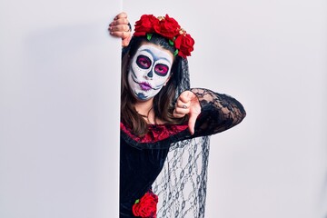 Poster - Young woman wearing day of the dead custome holding blank empty banner looking unhappy and angry showing rejection and negative with thumbs down gesture. bad expression.