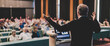 Speaker at Business Conference with Public Presentations. Audience at the conference hall. Business and Entrepreneurship concept. Rear view. Panoramic composition. Background blur.