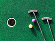 © Julia - Mini golf clubs and balls on putting green artificial grass carpet
