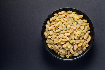 Wall Mural - Raisins in a black bowl on black background. Top view.