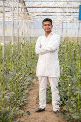 Portrait of Young happy indian farmer standing at his poly house or greenhouse, copy space, man with cross arm. agriculture.