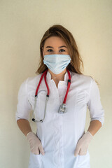 Wall Mural - Female nurse in white uniform and medical mask standing in clinic