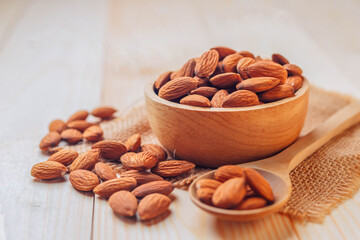 Almonds in a wooden bowl The nuts are freely placed on the dark board.