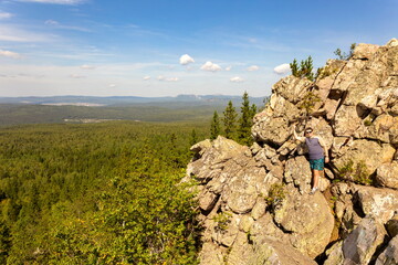 tourist man on the top of Aleksandrovskaya Sopka enjoy the Ural Mountains on a summer sunny day