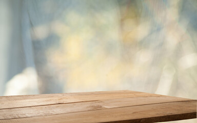 Empty wood table top seen from blur window with pine tree in snowfall of morning winter season. For a great product on the background concept.