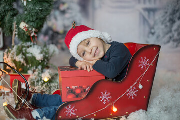 Sticker - Cute little toddler blond child, boy, sitting in sledge outdoors