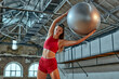 Beautiful woman in sportswear trains with a ball in the fitness room. Sports and technology concept. Lifestyle and health theme.