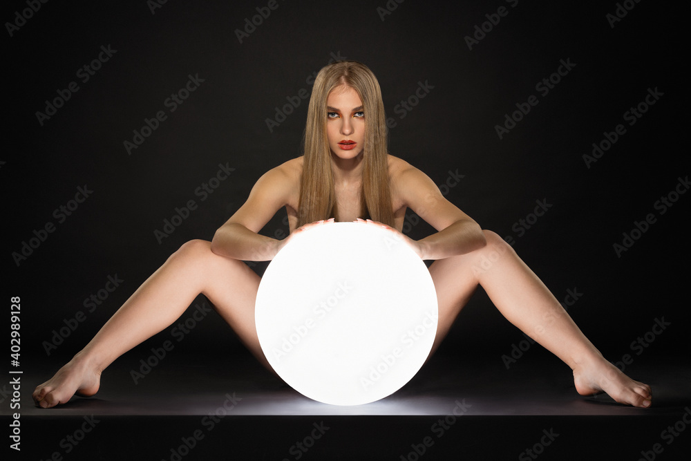 Wife spread legs blonde beautiful blonde girl posing wide spread her legs behind a large glowing  white ball on a black background Stock Photo | Adobe Stock