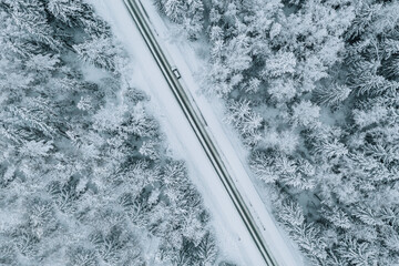Wall Mural - Aerial view of road with car in winter forest with snow.