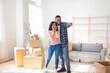 © Prostock-studio - Happy black guy hugging his excited girlfriend, dreaming about furniture placement, pointing somewhere in new house