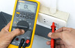 Digital multimeter in hands of electrician measuring volttage in a socket for detecting faults and safety before starting work