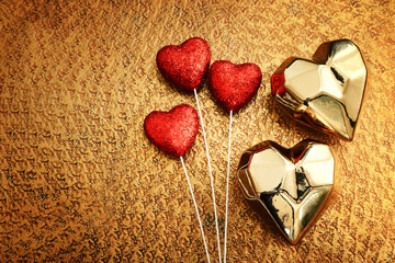 Sticker - Top view of gold and red glitter hearts over bronze background