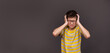 The boy is very emotional and tense, screaming in pain, holding his head. Boy annoyed by loud noise having panic attack screaming. On a gray background. Banner. Copy space. High quality photo