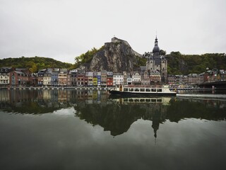 Panorama reflection of Dinant citadel old town historic village with boat in Meuse river Ardennes Namur Wallonia Belgium