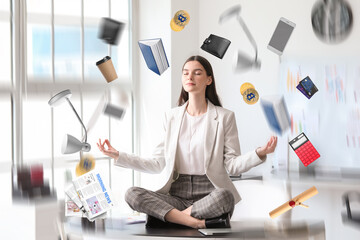 Wall Mural - Different things flying around young businesswoman meditating in office. Zen concept