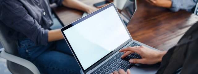 Mockup image of a woman using laptop with blank screen on wooden table