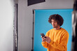 © Monkey Business - Studio Portrait Of Young Man Looking At Mobile Phone Against Blue Background