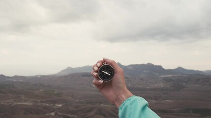 Wall Mural - Traveler explorer woman with a compass in a hand looking for direction in front of mountain. Point of view in first person.