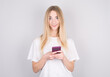 © Studio Nova - Portrait of a surprised attractive girl holding mobile phone and looking at camera isolated over white background