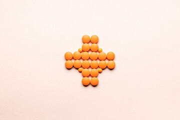 Wall Mural - pill cross shape isolated over pastel pink background. creative minimal. studio shot. above view. pharmacy concept