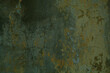 Background texture of cracked concrete wall with remnants of old green paint in a full frame view